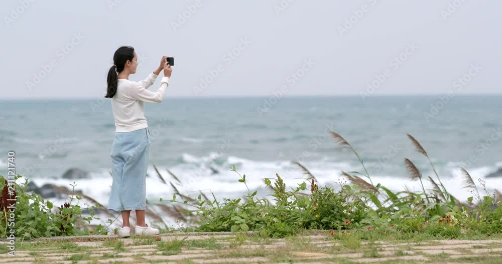 Woman taking photo on cellphone with the sea Woman taking photo on cellphone with the sea