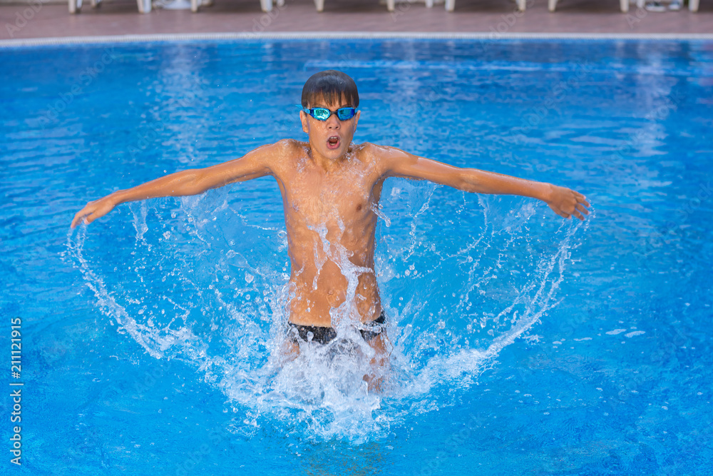 Boy, teenager, athlet having fun jumping in swimming pool.