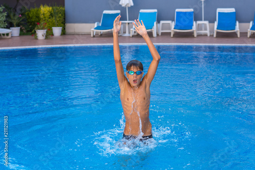 Boy, teenager, athlet having fun jumping in swimming pool.