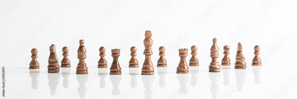 Wide panorama image of dark chess pieces on white table Wide panorama image of dark chess pieces on white table