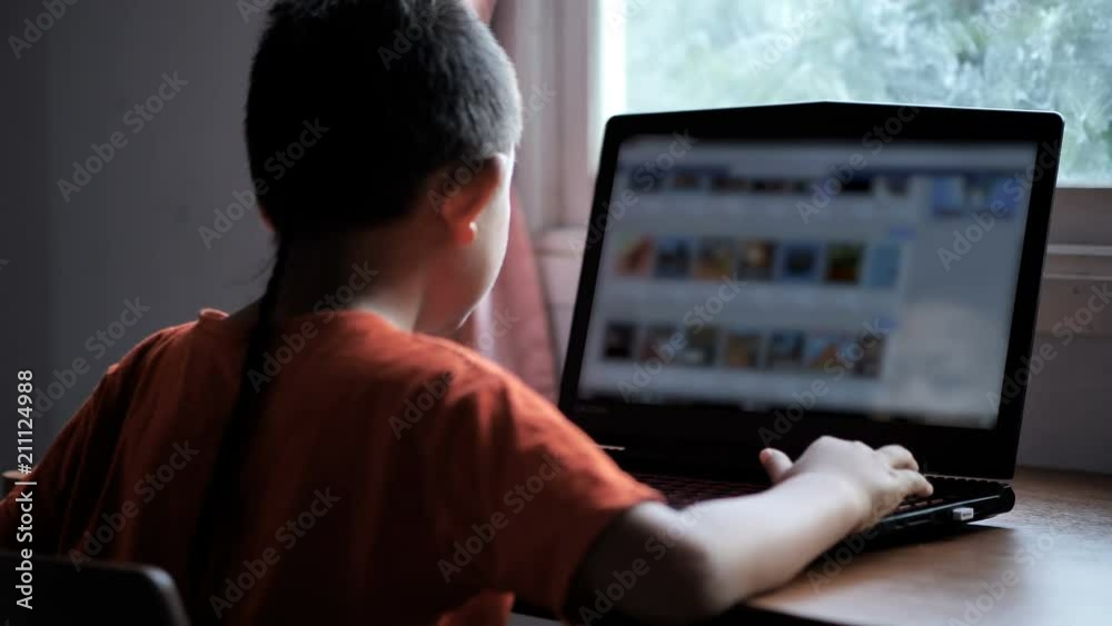 Asian boy 7 years old using laptop search Internet Information at home. Concept of technology in everyday life... Asian boy 7 years old using laptop search Internet Information at home. Concept of technology in everyday life...