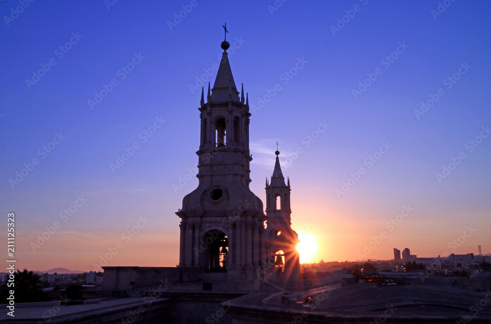 The warm light of setting sun shining through the bell tower of Basilica Cathedral of Arequipa, Peru