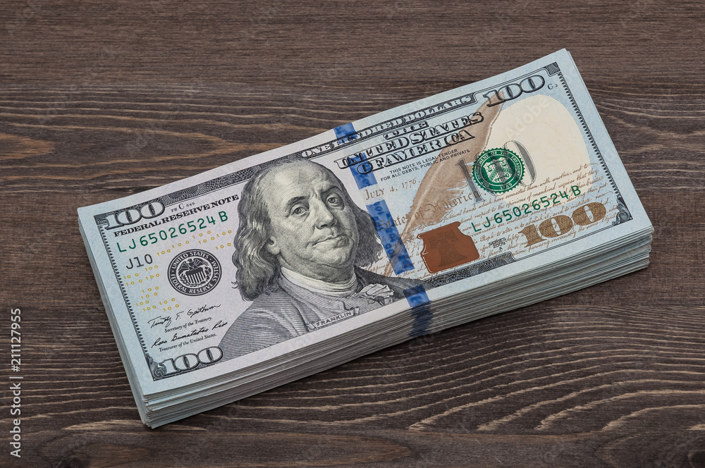 A bundle of denominations of ten thousand American dollars. against the background of a wooden table. Frontal side. A bundle of denominations of ten thousand American dollars. against the background of a wooden table. Frontal side.