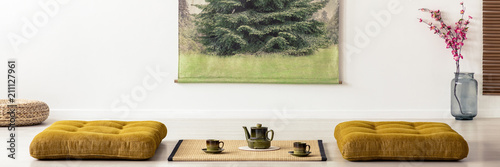 Photography Kettle and cups on tatami mat between cushions in dining room interior in a japanese design