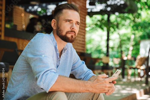Young bearded man outdoors using mobile phone