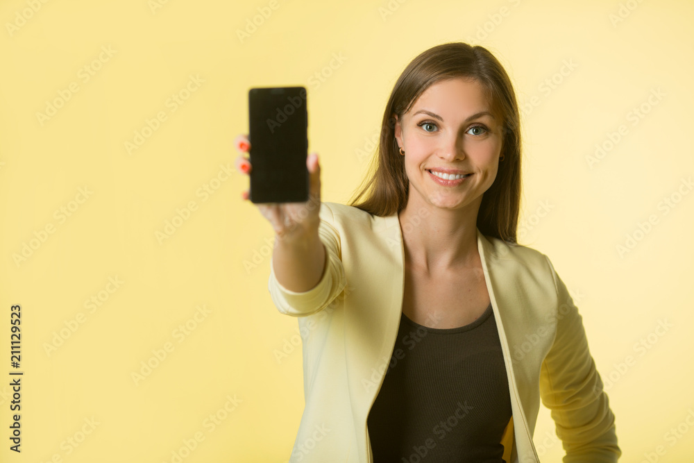 beautiful young girl in a yellow jacket on a yellow background with a phone in her hand beautiful young girl in a yellow jacket on a yellow background with a phone in her hand