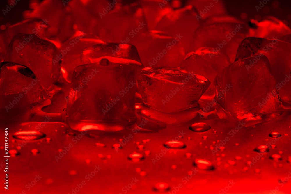 A bunch of red ice cubes on a reflecting table with drops of water close-up A bunch of red ice cubes on a reflecting table with drops of water close-up