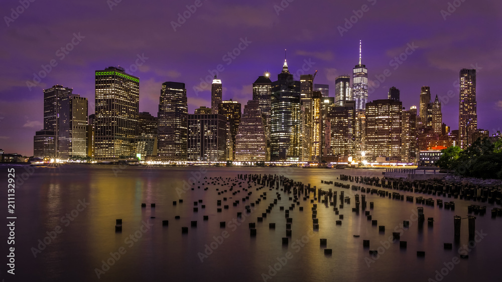 Fototapeta premium New York Skyline at night from Brooklyn with pillars arches in the foreground