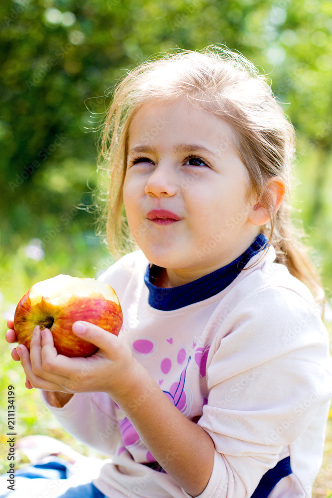 baby girl eating red apple in summer baby girl eating red apple in summer