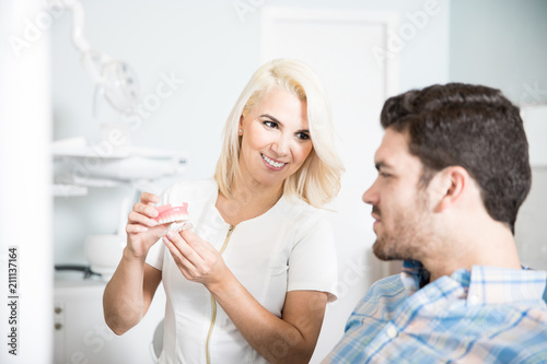 Dentist showing a teeth model to a patient