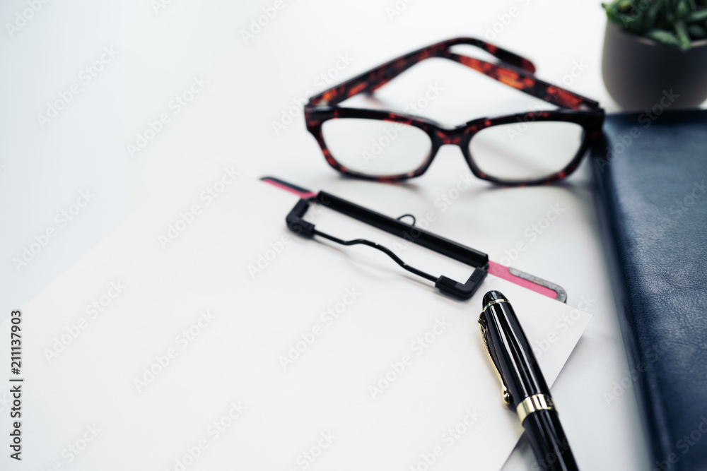 pen and clipboard with blank sheet, glasses on diary book on white background with copy space pen and clipboard with blank sheet, glasses on diary book on white background with copy space