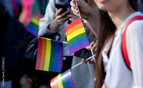 crowd waving rainbow flags at pride parade