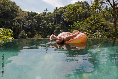girl in the tropic pool at inflatable ring