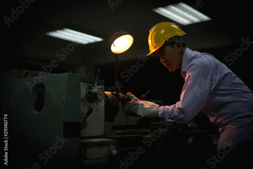 Asian engineer man wearing safety helmet checking and using an equipment in the laboratory. concept of manufacturing mechanical workshop measurement and tools.