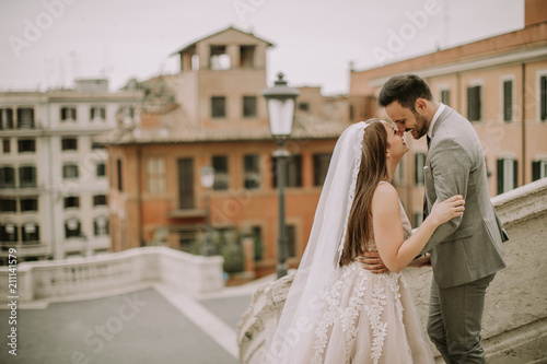 Young newly married couple posing in Rome with beautiful and ancient architecture in the background