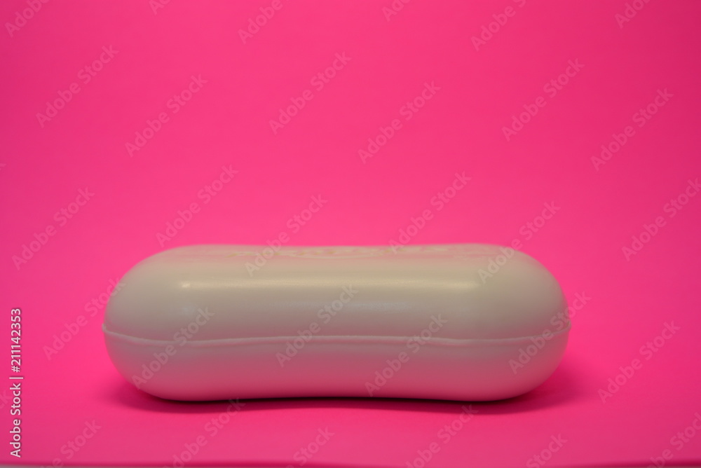 On a bright colorful pink paper background is located and placed a cosmetic antibacterial white soap for face and skin On a bright colorful pink paper background is located and placed a cosmetic antibacterial white soap for face and skin