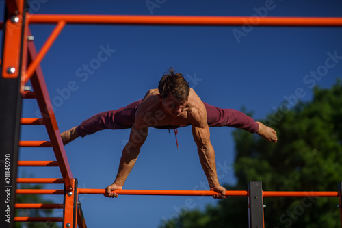 Muscular man making planche on the street. Street workout