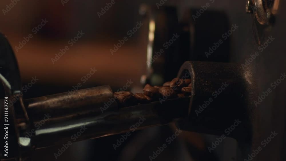 Cropped view of barista guy roasting coffee beans in special old machine, in slow motion