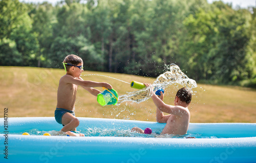 Kids, boys playing with water in a waterpool, vacations, holidays in a polish countryside.