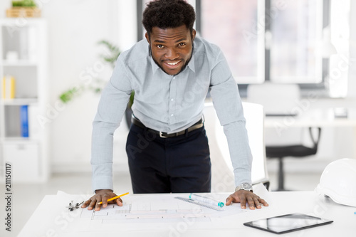 architecture, construction business and people concept - smiling african american architect with blueprint working at office