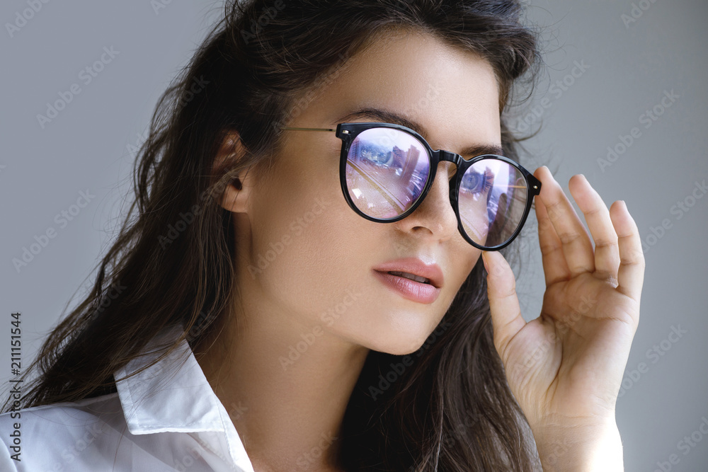 Close up portrait of Young woman with a reflection of modern city inside eyeglasses Close up portrait of Young woman with a reflection of modern city inside eyeglasses
