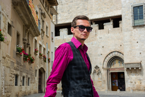 A young guy, a tourist stands on a street in Girona, Spain.
