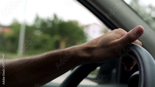 Man spinning steering wheel with one hand, car driving lessons, instructor