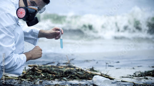 Toxicologist checking polluted water, splashing on shore, environmental disaster