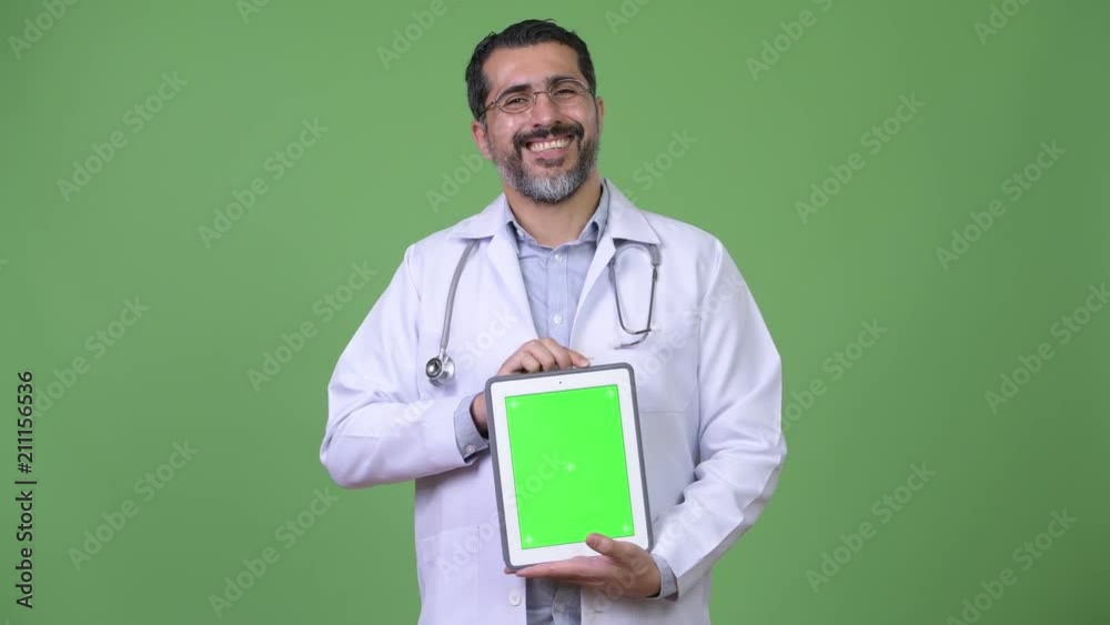 Handsome Persian bearded man doctor showing digital tablet Handsome Persian bearded man doctor showing digital tablet