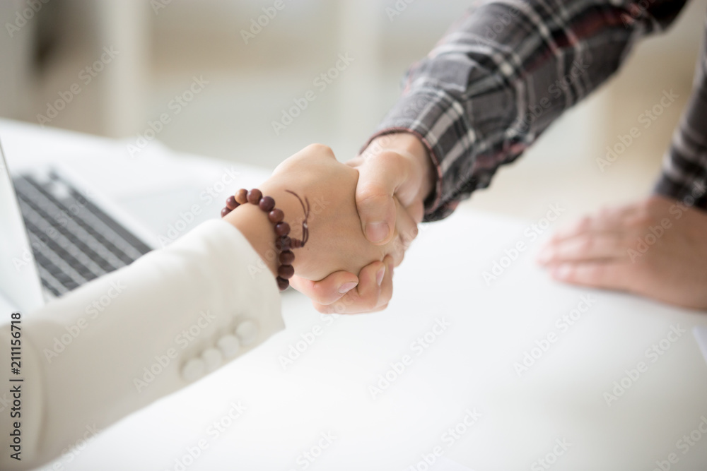 Close up of diverse handshake, male employer shaking hand of female job candidate, congratulating with successful work interview, welcoming to business team. Concept of hiring, employment, HR