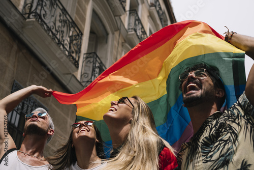 Group of friends with a flag of gay pride in the city of Madrid