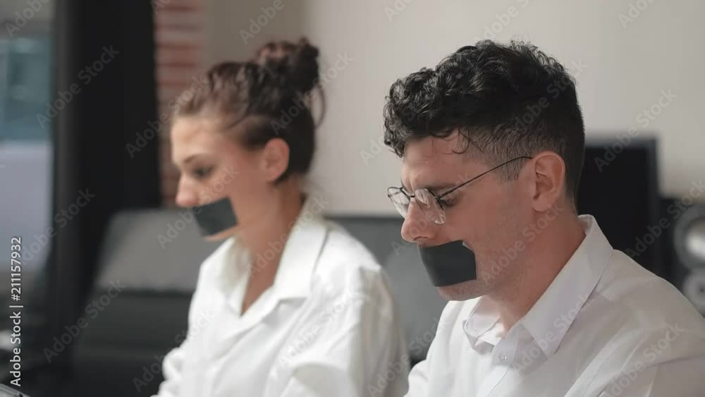 Workers are sitting with sticky tape on mouth Workers are sitting with sticky tape on mouth