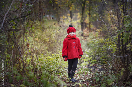 Little girl in a red coat at autumn