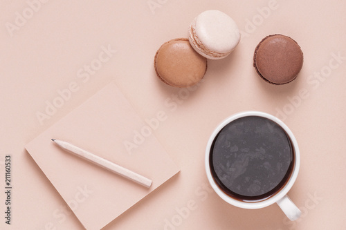 Cup of coffee with macaroons on pastel background.