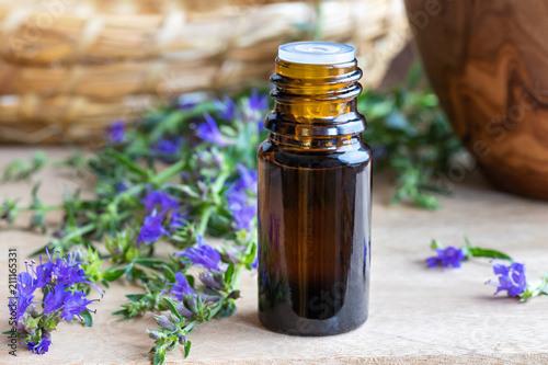 A bottle of hyssop essential oil with fresh blooming hyssop photo