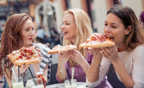Female friends eating pizza in cafe