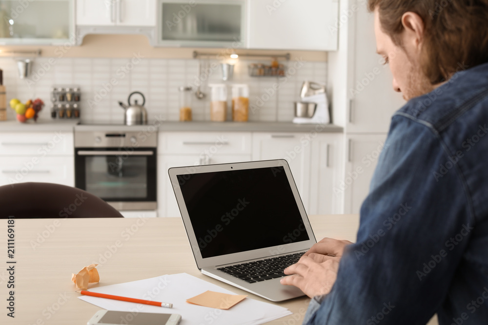 Young man working with laptop at desk in home office Young man working with laptop at desk in home office