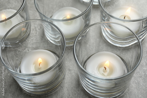Beautiful burning wax candles in glasses on table