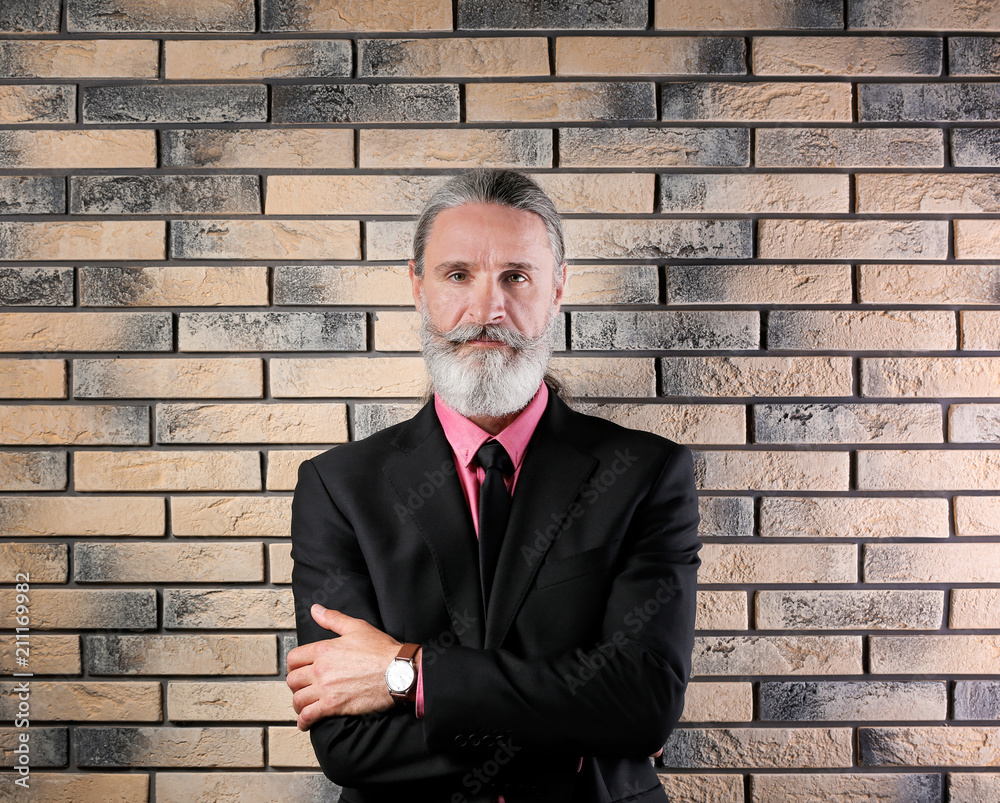 Handsome bearded mature man in suit near brick wall background Handsome bearded mature man in suit near brick wall background