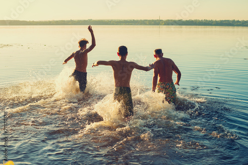 Joyful friends run into the water in a cloud of spray