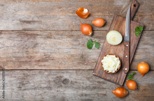 Flat lay composition with fresh ripe onions on wooden table
