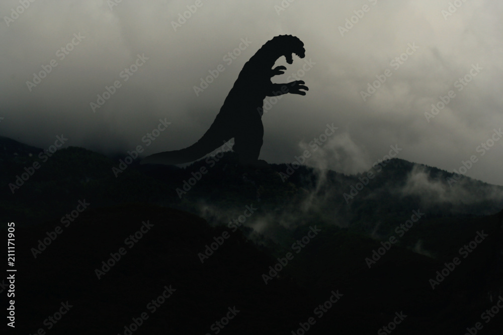 Fototapeta premium Silhouette eines Godzilla-artigen Monsters im Nebel auf einem Berg