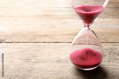 Hourglass with flowing sand on table. Time management