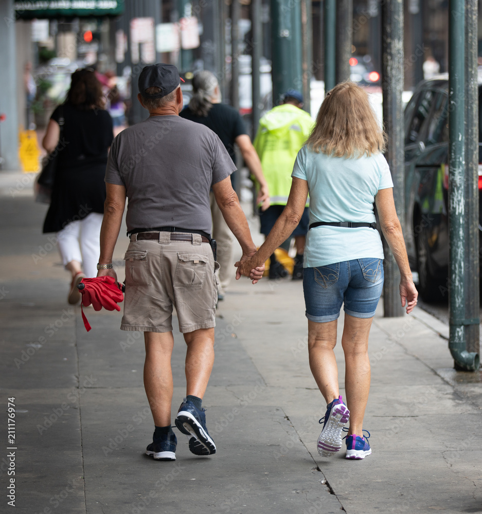 unknown happy couple holding hands for a walk downtown