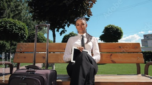 Beautiful business woman stand with lagguage and phone while standing near airport, woman talk smartphone. Brunette sexy businesswoman in suit and tie near modern business center office building photo