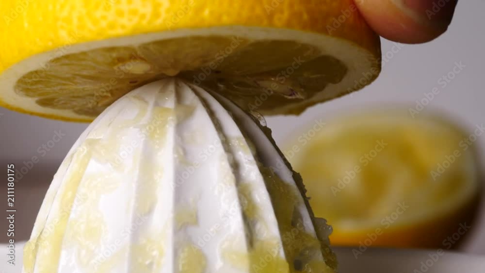 Slow motion shot of human male hand squeezing lemon juice using manual white fruit juicer