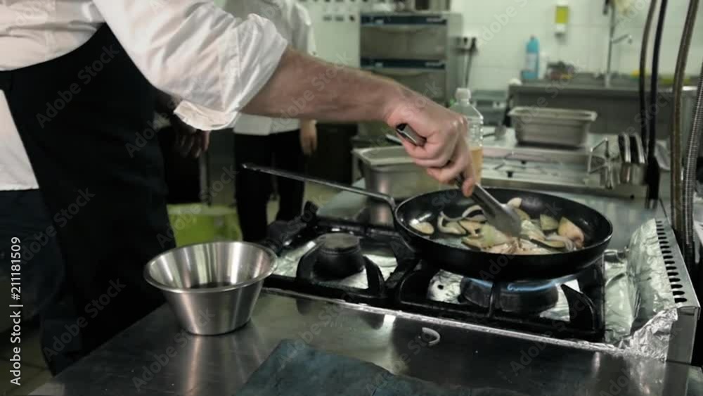Chef is making flambe sauce on restaurant kitchen with onion and wine Chef is making flambe sauce on restaurant kitchen with onion and wine