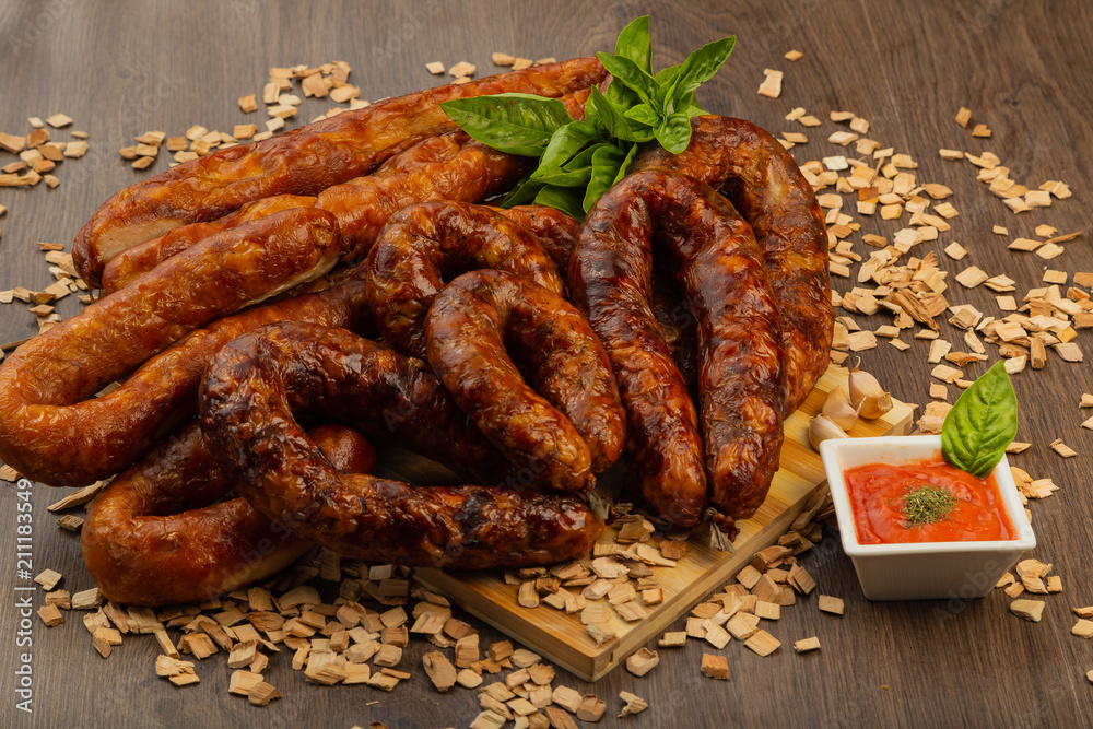 Homemade sausage on a wooden background with seasonings and sauce.