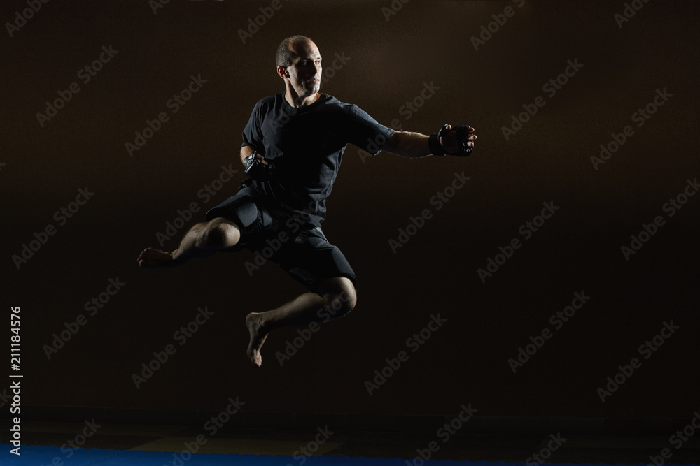 A sportsman in MMA gloves is training a jump for a punch hand