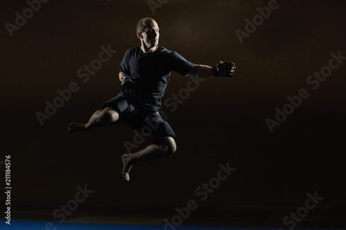 A sportsman in MMA gloves is training a jump for a punch hand © andreyfire